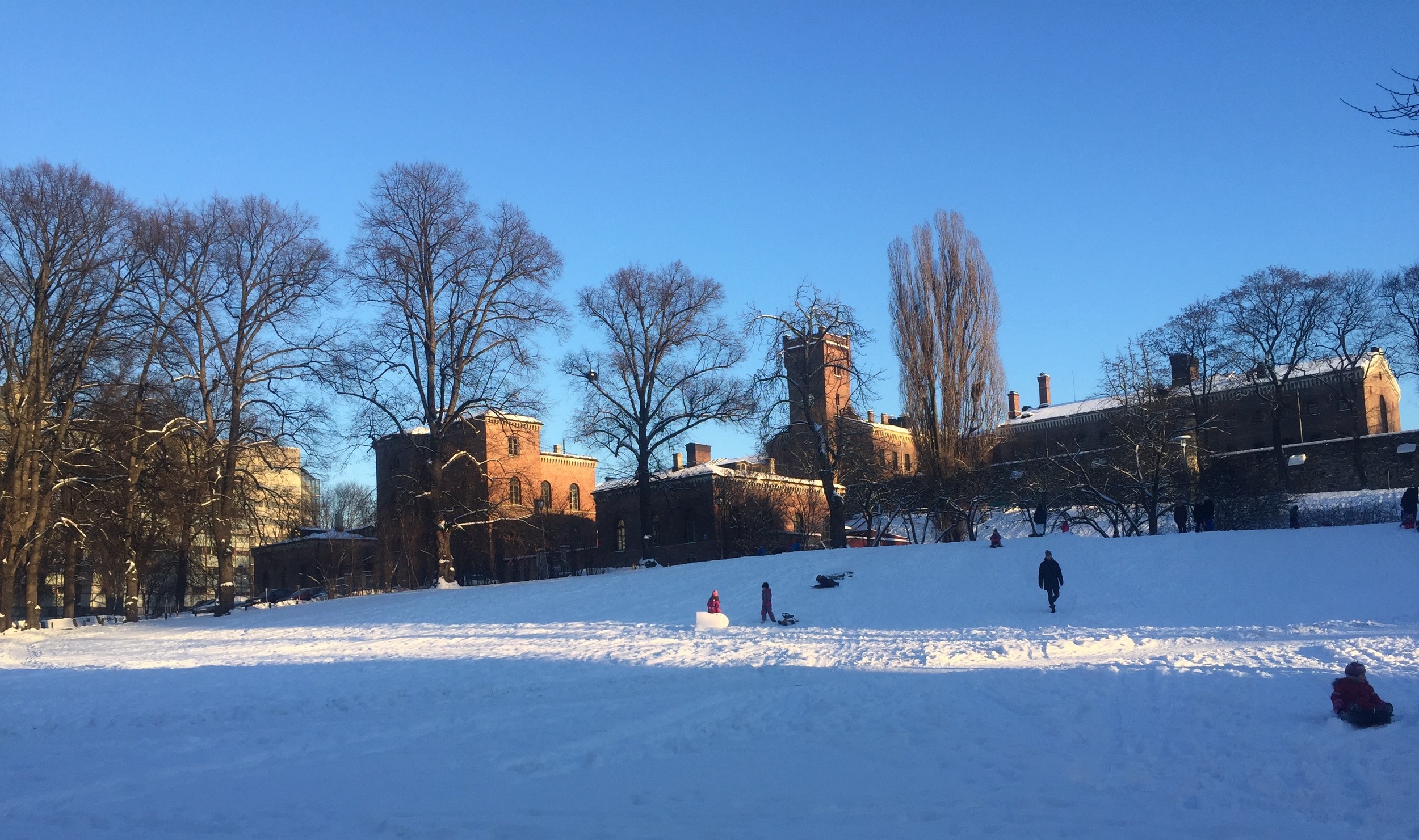 Botsfengselet i bydelen Grønland i Oslo, badet i sol. Foran ligger den snødekte akebakken, som er en yndet ake- og lekeplass for barn.