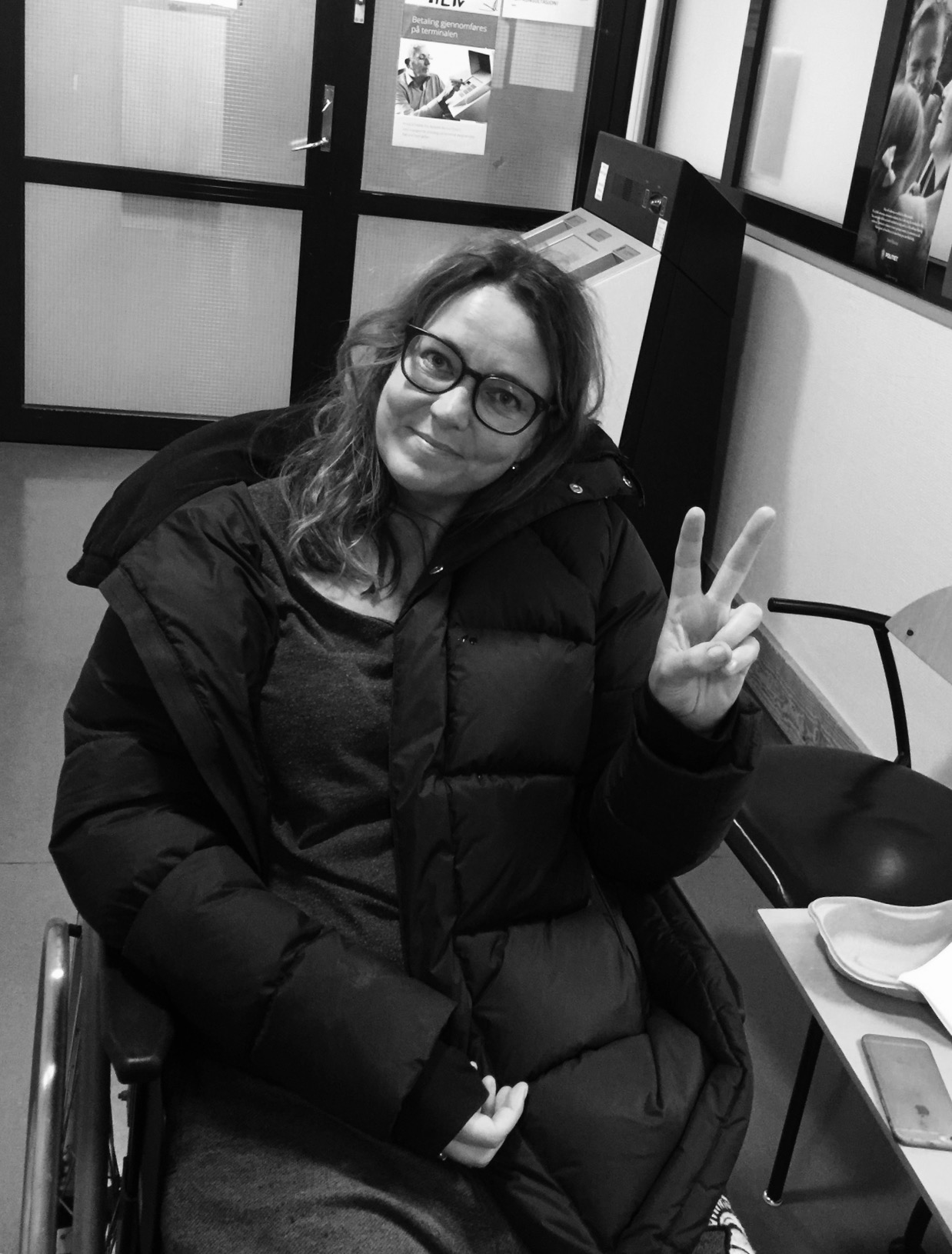 På legevakten på tampen av 2016: Smertetårene er tørket opp. Jeg får en rullestol å sitte i, og smiler tappert mens jeg gjør V-tegnet. 